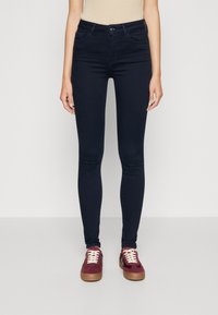 Mörkblå slim fit jeans i elastisk denim, med hög midja, fram- och bakfickor samt diskreta sömnadsdetaljer.
