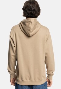 Beige hoodie met een trekkoord capuchon, ribbels aan de mouwen en onderkant. Gemaakt van een zachte stof; heeft een gladde textuur en een relaxed fit.