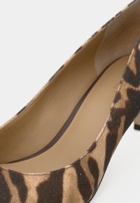 Γόβα με τακούνι σε λεοπάρ σχέδιο, με μπεζ εσωτερική επένδυση και στρογγυλεμένη μύτη, σε κοντινή λήψη.