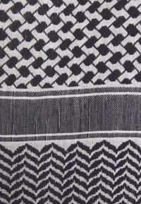 Tkanina z geometrycznym wzorem w kształcie diamentów w ciemnym niebieskim kolorze na białym tle, uzupełniona poziomymi paskami o różnych fakturach.