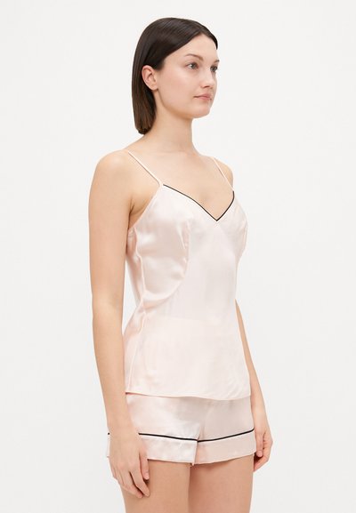Light pink satin camisole with thin straps, featuring a V-neckline and black piping; paired with matching satin shorts.