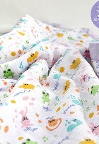Soft white baby blanket with colorful prints of frogs, bees, cats, snails, and musical notes scattered across the fabric.