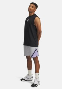Svart ärmlös tröja, grå meshshorts med lila detaljer, vita strumpor och svart-vita träningsskor. Enkel design, avslappnad passform.