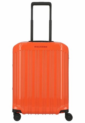 Valise rigide orange avec des rayures verticales, poignée rétractable noire et quatre roues pour la mobilité. Design durable et élégant.