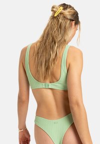 Mintgrön ribbad bikiniöverdel med tjocka remmar och spänne, kombinerad med matchande högmidjade bottnar. Har texturerad tyg.