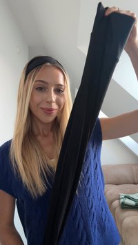 Juodos medvilnės leggingai, laikomi aukštai, su lygiu paviršiumi ir prigludusia forma. Fone matoma šviesios spalvos sofa ir antklodė.