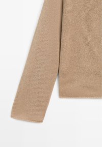 Beiger gestrickter Pullover mit langen Ärmeln, gerippten Bündchen und sichtbarer Maschenstruktur auf weißem Hintergrund.