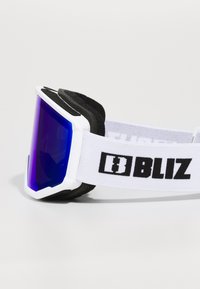 Lunettes de ski avec une monture blanche, des verres miroir bleus et un rembourrage en mousse noire. La sangle réglable arbore un logo "BLIZ" en noir.