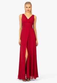 Abito in chiffon rosso con scollatura a V, corpino plissettato e spacco alto. Silhouette fluida e design senza maniche, arricchito da una vita aderente.