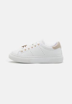 Białe skórzane sneakersy z złotymi oczkami, teksturowanym beżowym akcentem na pięcie oraz białą gumową podeszwą. Na bokach znajdują się perforacje zapewniające wentylację.