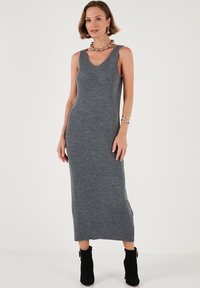 Gray ribbed knit dress with a V-neck and sleeveless design. The dress falls to mid-calf, paired with black ankle boots.