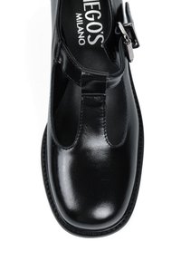 Czarne, polerowane skórzane buty T-bar z okrągłym noskiem, regulowanym metalowym zapięciem i wycięciami po bokach. Gładka faktura i szyta krawędź.