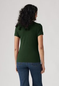 Groene polo-shirt met korte mouwen en een comfortabele pasvorm, gemaakt van zachte stof; heeft een effen ontwerp en een rechte zoom.