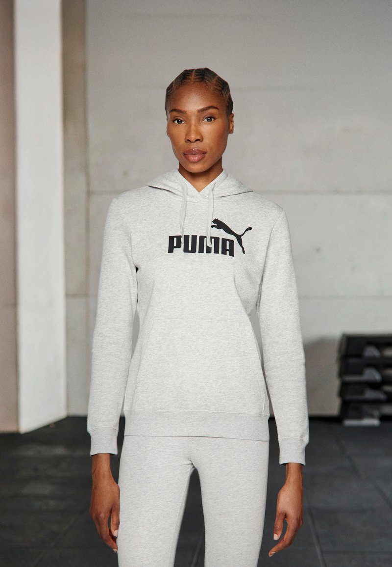 Svetlošedá mikina s kapucňou a čiernym logom "PUMA" a dizajnom mačky, so šnúrkou na kapucni a rebrovanými manžetami, v kombinácii s koordinačnými legínami.