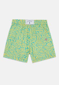 Costumi da bagno blu vivo e gialli con un motivo ripetuto "GUESS", cintura elasticizzata e un piccolo dettaglio viola.