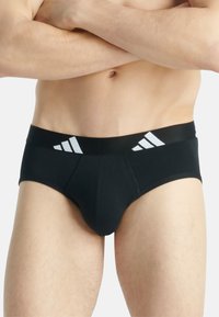 Svarta herrkalsonger med en bred svart midjeband och tre vita ränder. Gjorda av mjukt tyg med en slät textur.