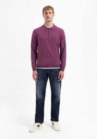 Paarse langemouwen polo met een ritskraag, gecombineerd met blauwe jeans en witte sneakers, met een casual pasvorm en een gestructureerde stof.
