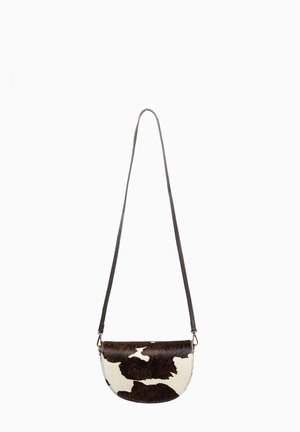 Pequeño bolso bandolera en forma de media luna con una larga correa negra, con un estampado de piel de vaca en blanco y negro en la solapa y el cuerpo.