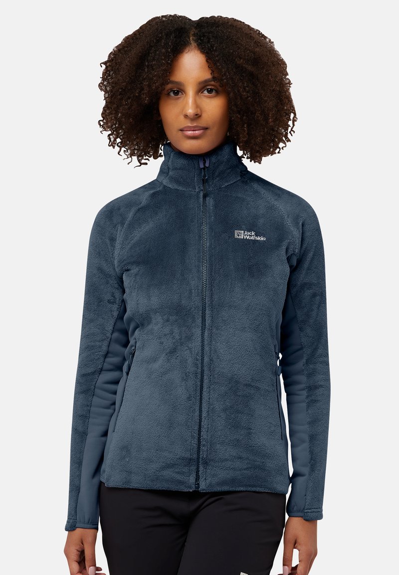 Giacca in pile blu navy con colletto alto, chiusura con zip e tasche laterali. Tessuto morbido con pannelli a contrasto elasticizzati e dettaglio del logo sul petto.