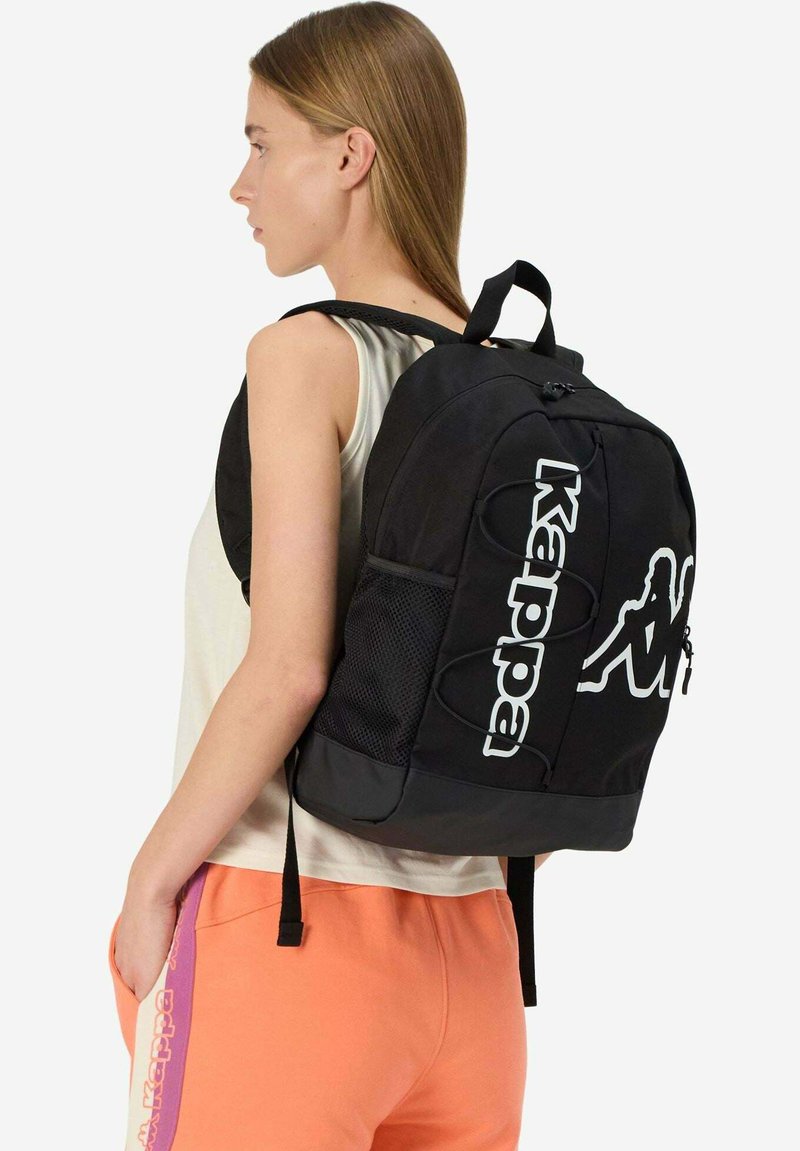 Zaino nero con una finitura testurizzata, caratterizzato dal logo Kappa, tasca laterale in rete e spallacci regolabili. Design semplice e funzionale.