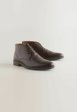 Hnedé kožené kotníkové topánky s hladkým povrchom, šnurovacia uzávierka a zaoblená špička. Obsahujú jemný textúrovaný detail na vrchu.