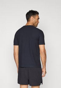 Navy-blaues Kurzarm-T-Shirt aus einem strukturierten Stoff, mit Rundhalsausschnitt und lockerer Passform, kombiniert mit dunklen Shorts.