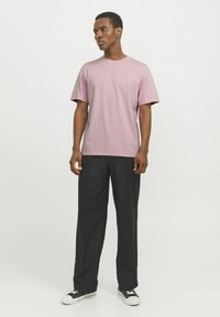 Pink kortærmet t-shirt med rund hals, kombineret med sorte wide-leg bukser og sorte sneakers med hvid sål. Enkelt, glat tekstur.