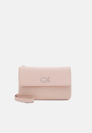 Pochette en cuir rose clair avec rabat et logo CK argenté, avec une sangle de poignet sur fond blanc.