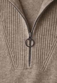Maglione beige con texture a coste e chiusura a metà zip. Presenta una zip argentata con tirante circolare e accentuazioni texture vicino al collo.