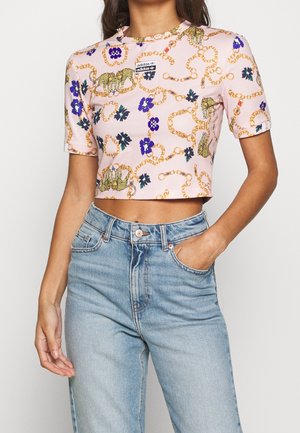 Haut rose raccourci à manches courtes, avec motifs de chaîne dorée, léopard et fleurs ; étiquette sur la poitrine ; tissu lisse et extensible.