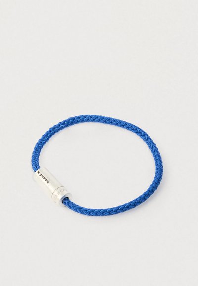 Kék fonott zsinór karkötő, hengeres ezüst kapoccsal, amelyen az "le gramme" és a "925" felirat található.