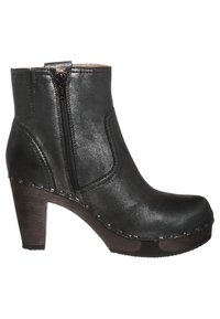 Bota de cuero negro hasta el tobillo con una cremallera lateral, tacón grueso y costuras detalladas a lo largo de la suela. Textura suave con un acabado pulido.