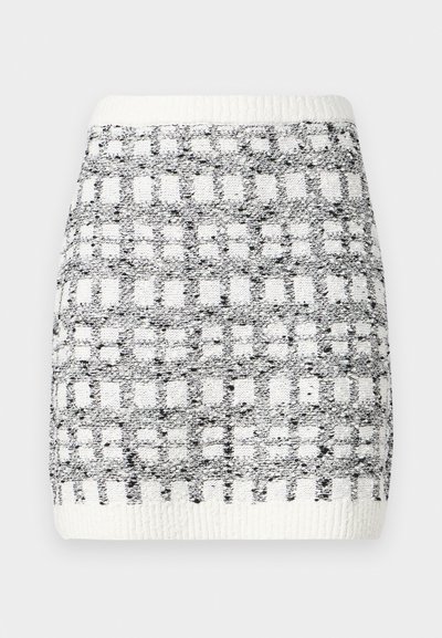 Knit skirt in black and white with a square pattern, featuring a ribbed waistband and textured surface. Above-the-knee length.