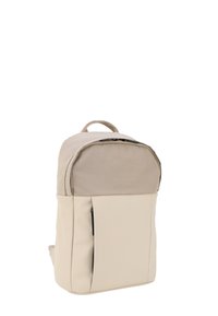 Mochila beige con una parte superior texturizada y una sección inferior suave, cuenta con un cierre de cremallera, un bolsillo frontal y una asa superior para llevar.