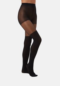 Pantys negras con parte superior transparente, que presentan una textura suave y un color sólido. El diseño incluye una banda en el muslo y una puntera reforzada.