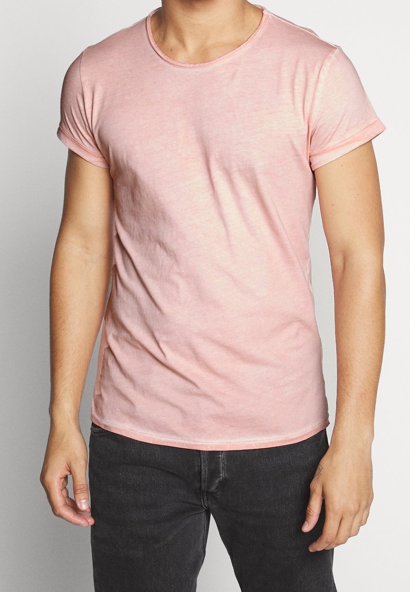 Lyserød bomulds t-shirt med rund hals, korte ærmer og opbrettede manchetter. Blød tekstur, tætsiddende design og subtil meleret mønster.