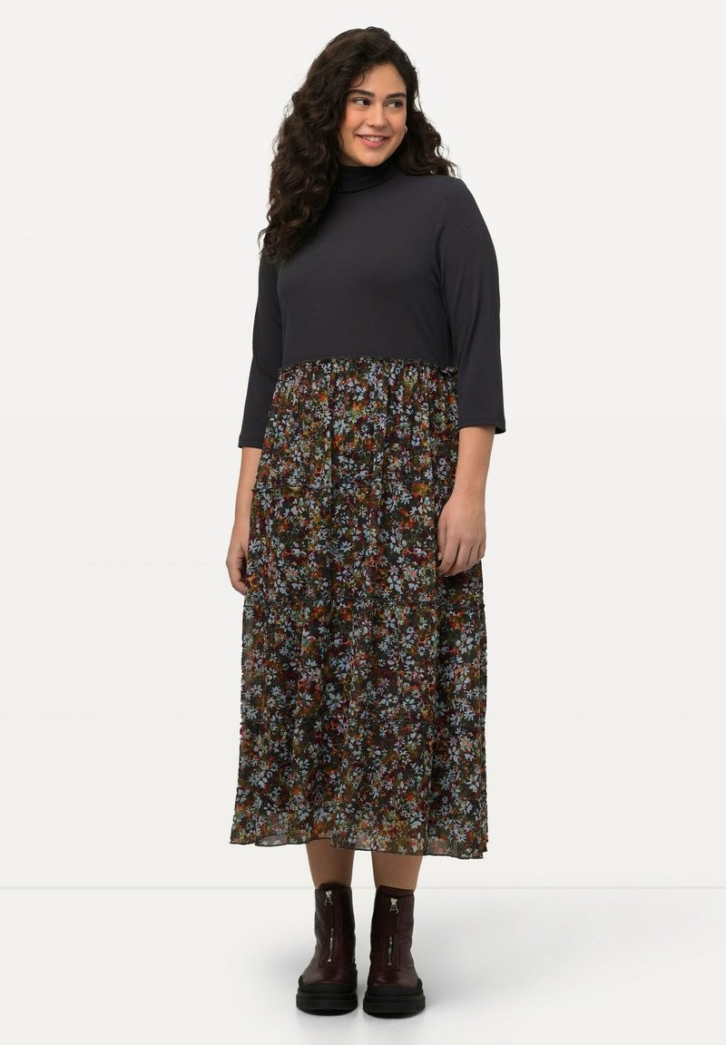 Czarna ribbed bluzka z wysokim dekoltem i rękawami 3/4, połączona z d�ługą spódnicą w kwiecisty wzór w różnych kolorach. Uzupełniona botkami za kostkę.