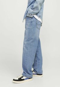 Lichtblauwe relaxte jeans van denim, met een rechtvallend ontwerp en klassieke achterzakken, gecombineerd met zwart-witte sneakers.