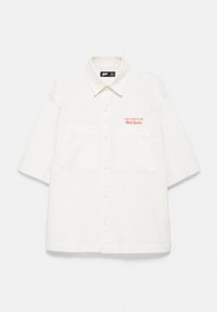 Chemise blanche à manches courtes boutonnée avec deux poches avant et texte rouge « State Competition Stand Studio » sur la poitrine gauche.
