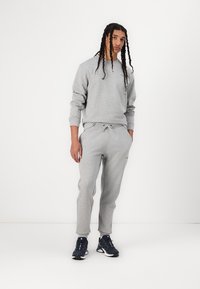 Gray cotton sweatshirt and sweatpants set with a relaxed fit, featuring elastic cuffs, drawstring waist, and side pockets.