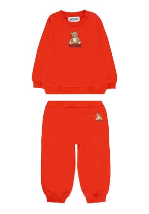 Jasnopomarańczowy zestaw baby bluzki i spodni z grafiką misia oraz napisem "Moschino" na górze i na spodniach.