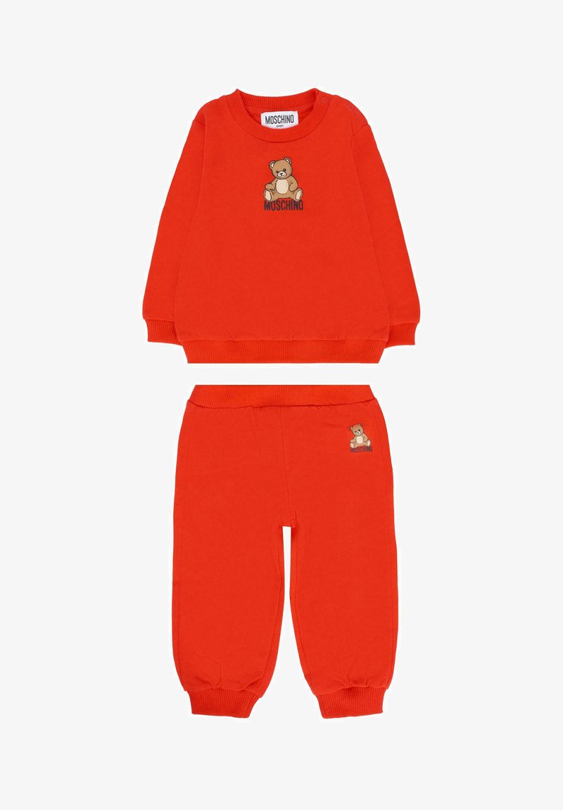 Felgroene babysweater en broekset met teddybeerafbeelding en "Moschino" tekst erboven en op de broek.