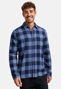 Blauwe geruite shirt met donkere en lichte blauwe vierkanten, knoopsluiting aan de voorkant en lange mouwen. Zachte stof met een casual pasvorm.