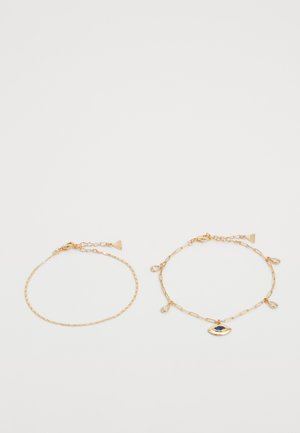 Twee goudkleurige armbanden met een delicate kettingontwerp. De ene heeft een eenvoudige ketting, de andere bevat een centraal oog-bedel met accenten.