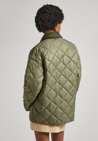 Chaqueta acolchada de color verde oliva con un patrón de diamantes, con un cuello sólido y mangas largas, hecha de un material liso y ligero.