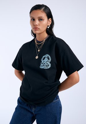 Schwarzes Baumwoll-T-Shirt mit einem blauen abstrakten Grafikdesign auf der Brust, ergänzt durch entspannte Ärmel und einen Rundhalsausschnitt.