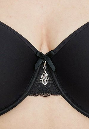 Black bra featuring smooth fabric cups, lace underlay, a center bow, and a metallic hand charm embellishment at the front.