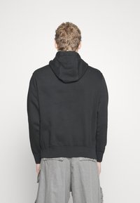 Black hooded sweatshirt with a soft texture, elastic cuffs, and bottom hem. The back features a simple, clean design without embellishments.