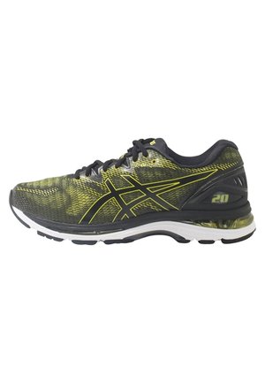 Chaussure de course noire et jaune avec empeigne en mesh, lacets noirs, semelle blanche et talon rembourré marqué de "20" sur le côté.