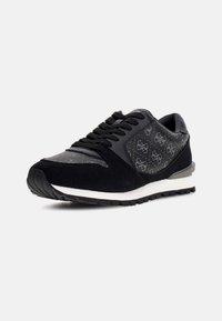 Sneaker nera con tomaia in suede e mesh, dotata di una pannello laterale a motivo, lacci neri, suola intermedia bianca e suola esterna in gomma texturizzata.